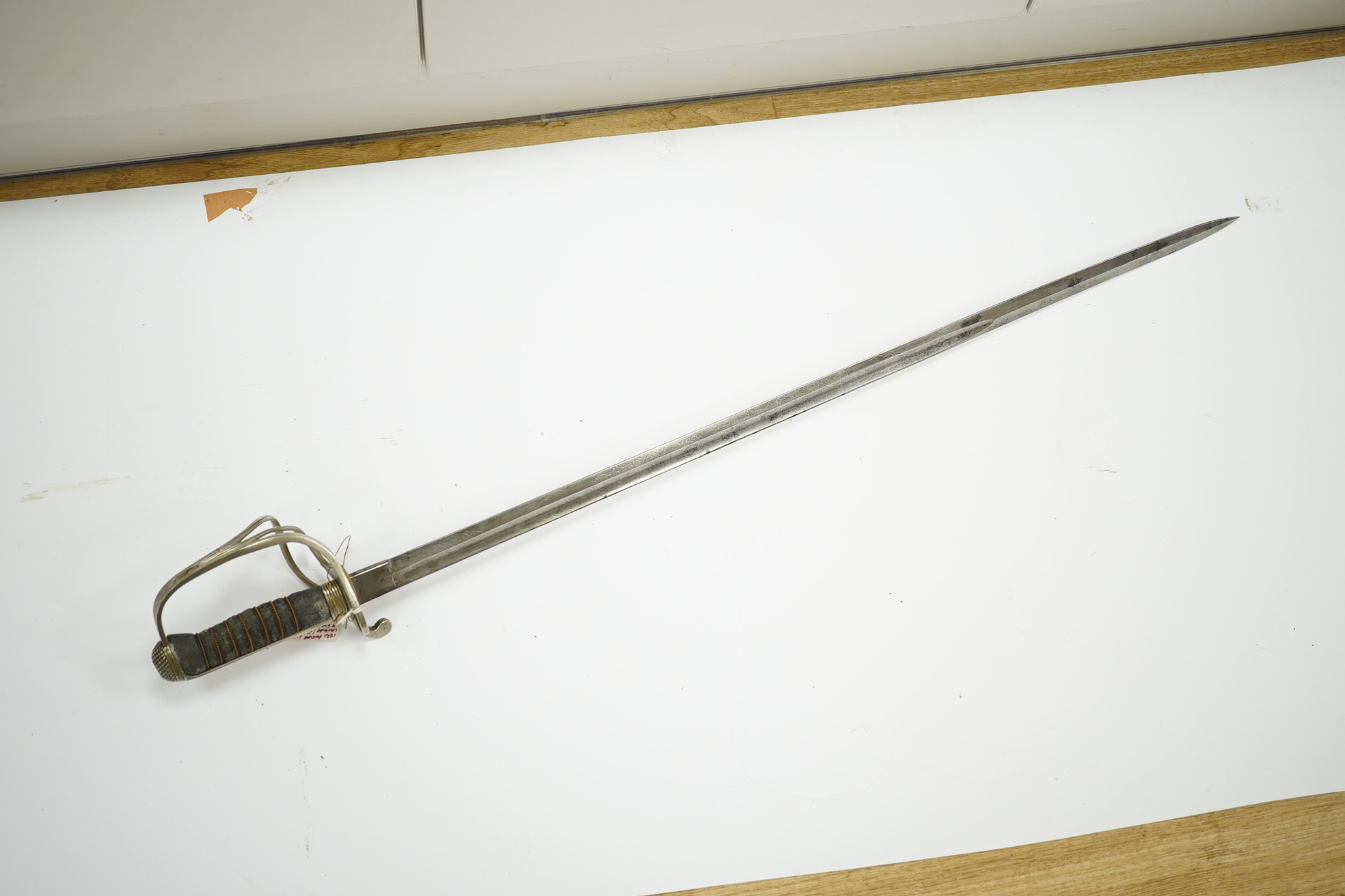 An 1821 pattern GVIR light cavalry officer’s sword in its leather scabbard, Royal Army Service Corps, blade etched with owners initials; JNDA and also with initials RASC, with regulation nickel guard, in its leather fiel